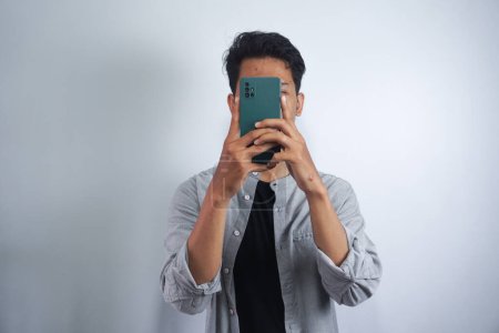 Photo for Smile please! Time for a sweet click. Closeup portrait of a young man taking a picture using a handphone - Royalty Free Image