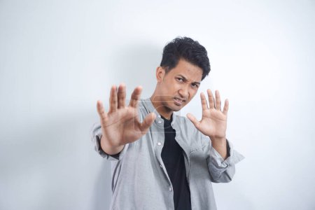 Photo for Attractive Asian man makes frightened gesture with palms, defends himself from someone, asks to stop it immediately. Guy says stay away from me, shows stop sign. Body language concept - Royalty Free Image