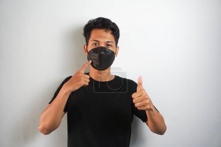 Photo for Man wearing medical mask and giving thumbs up, Isolated person wearing medical mask giving thumbs up. - Royalty Free Image