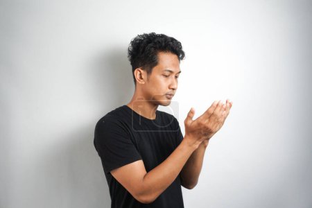 Photo for Young handsome man praying wearing black t shirt. Person isolated against white background. - Royalty Free Image