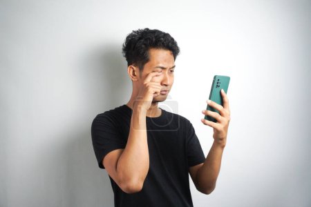 Photo for Stressed man receiving message with bad news on smartphone, shock and crying - Royalty Free Image