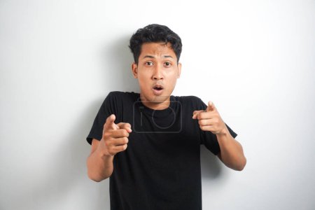 Photo for Happy excited and smiling young Asian man raising his arm up to celebrate success or achievement. Indonesian man wearing black t-shirt - Royalty Free Image