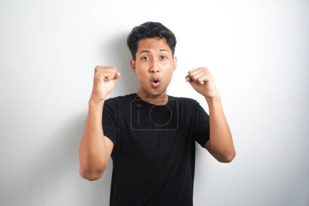 Photo for Excited Asian man celebrating success with two fists in air isolated on the white background. close up portrait, studio shot , happiness, positive emotion and feeling. I've done it. facial expression - Royalty Free Image