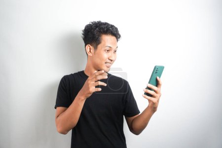 Photo for Wow face of Your Asian man shocked what he see in the smartphone on isolated grey background. Indonesia Man wear black shirt Isolated grey background. - Royalty Free Image