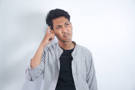 Photo for Young man with shirt having doubts and with confuse face expression while scratching head on isolated white background - Royalty Free Image