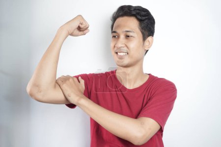 Photo for Young asian man wearing t-shirt standing over isolated white background Strong person showing arm muscle, confident and proud of power - Royalty Free Image