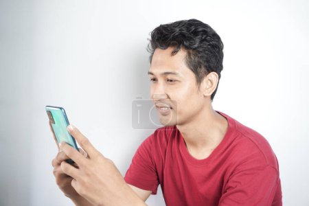 Photo for Asian man seriously looking at cellphone - Royalty Free Image