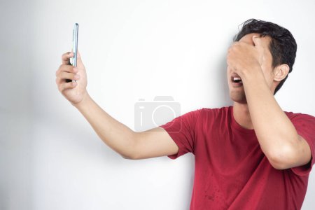 Photo for Man is shocked to see social media on his cellphone displaying obscene or vulgar content so he reflexively closes his eyes - Royalty Free Image