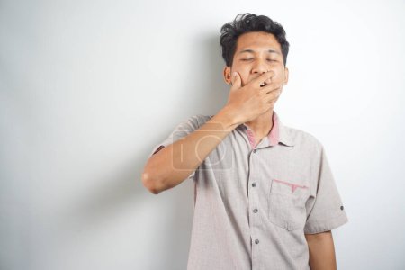 Photo for A tired man wearing a shirt is yawning - Royalty Free Image