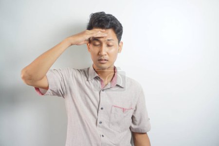 Photo for Horizontal photo of good-looking asian man pictured isolated on white background showing how much his head hurts, experiencing pain, looking miserable and exhausted - Royalty Free Image