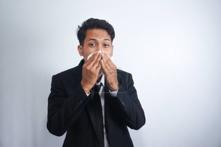Photo for Horizontal portrait of unhealthy handsome man wearing suit, blowing nose into tissue. Male have flu, virus or allergy against white background. Healthy medicine and people concept - Royalty Free Image