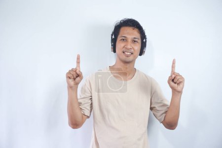 Photo for Asian man wearing headphones smiling amazed and surprised and pointing up with fingers and raised arms. isolated on white background - Royalty Free Image
