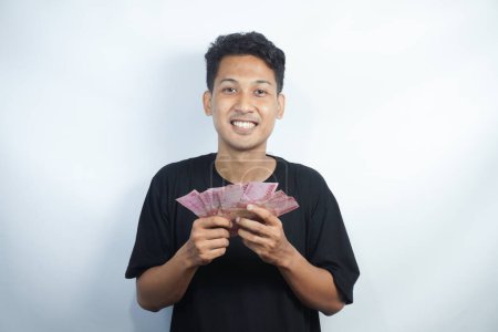 Photo for Image of shocked and happy handsome young Asian man posing isolated over white wall background holding bunch of money cash - Royalty Free Image