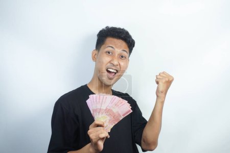 Photo for Image of shocked and happy handsome young Asian man posing isolated over white wall background holding bunch of money cash - Royalty Free Image