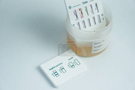 Photo for Examination of narcotic content in urine by placing the urine in a urine container and then immersing a portion of the drug test kit in the urine. isolated on white - Royalty Free Image
