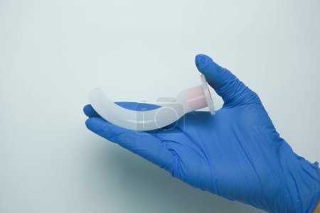 Photo for Medical worker wearing medical gloves holding an OPA (Oropharyngeal airway) is a medical device called an airway adjunct that is used in airway management to maintain or open a patient's airway - Royalty Free Image