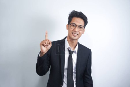 Photo for Attractive young Asian man in suit pointing up with his finger isolated on white background - Royalty Free Image