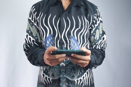 Photo for Man wearing batik shirt using cellphone - Royalty Free Image
