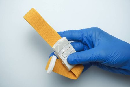 Photo for Doctor wearing blue medical gloves holding a yellow tourniquet, isolated on white - Royalty Free Image
