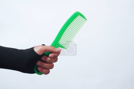 Photo for Female hand holding hair accessories green comb over white background, copy space. Set of hairdresser's tools on white background - Royalty Free Image