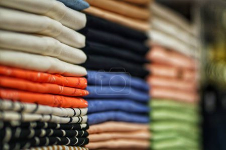 Photo for Piles of colorful clothes neatly arranged on a clothing store shelf. - Royalty Free Image