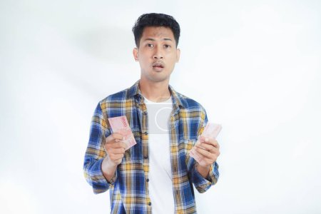 Erwachsener asiatischer Mann zeigt enttäuschten Gesichtsausdruck, während seine beiden Hände Papiergeld halten
