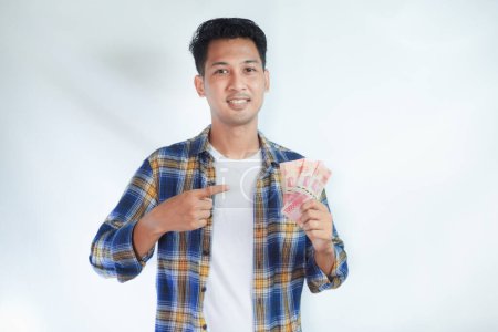Erwachsener asiatischer Mann lächelt, während er auf Geld zeigt, das er in der Hand hält