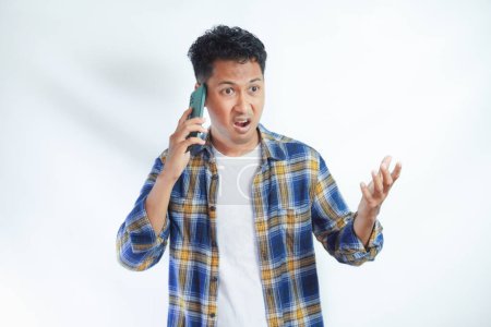 Photo for Adult Asian man showing angry expression when answering a mobile phone call - Royalty Free Image