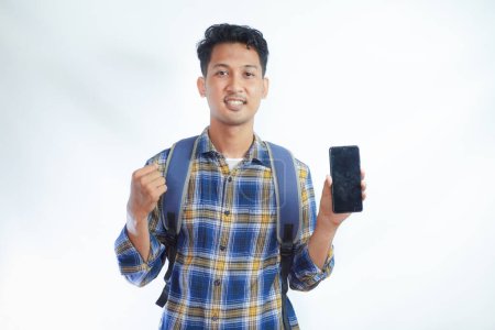 Photo for Smiling young Asian man student in casual clothes and glasses backpack showing mobile phone with blank screen, recommends new app isolated on white background. high school university college - Royalty Free Image