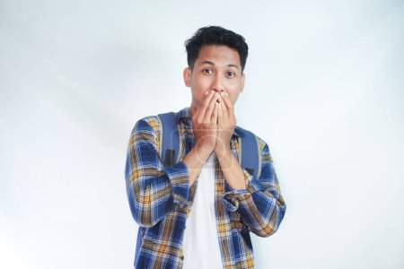 Photo for Portrait of shocked young Asian man student wearing casual shirt backpack covering mouth with hand and looking at camera isolated on white background. high school university college concept - Royalty Free Image
