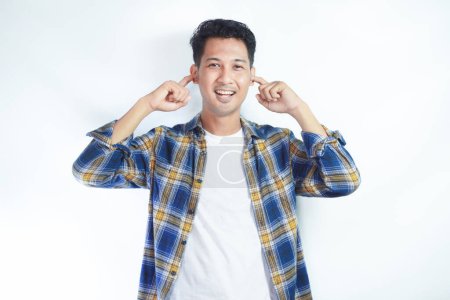 Adulto asiático hombre sonriendo mientras cubre sus oídos con el dedo