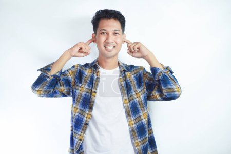Ein erwachsener asiatischer Mann lächelt, während er seine Ohren mit dem Finger bedeckt