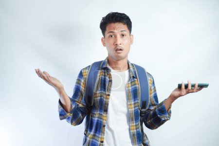 Un jeune étudiant asiatique perplexe ne sait pas quoi faire sur fond blanc dans un studio isolé sur fond blanc. École secondaire université concept collège