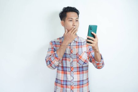 Téléchargez les photos : Asiatique homme regardant à son téléphone avec l'expression de choc - en image libre de droit