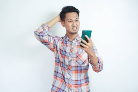 Foto de Adulto asiático hombre mirando a su teléfono móvil con desesperada expresión - Imagen libre de derechos