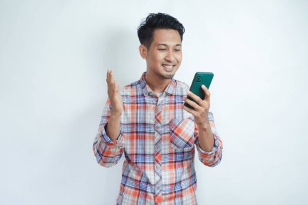 Photo for Adult Asian man looking to his mobile phone with happy expression - Royalty Free Image