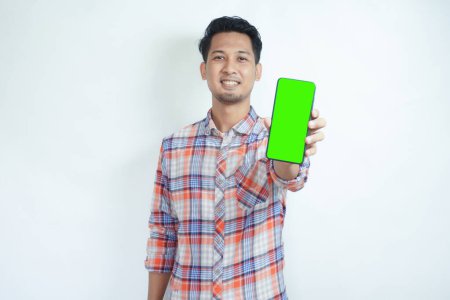 Adulte asiatique homme debout tout en souriant montrant vert écran de téléphone portable qu'il tient