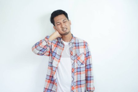 Erwachsener asiatischer Mann berührt Nackenrücken mit Schmerzausdruck