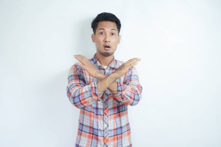 Adult Asian man wearing flannel shirt making stop hand sign with serious expression