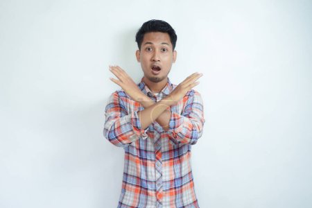 Adult Asian man wearing flannel shirt making stop hand sign with serious expression