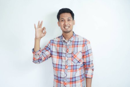 Erwachsener asiatischer Mann lächelt freundlich und gibt mit den Fingern "OK" -Zeichen