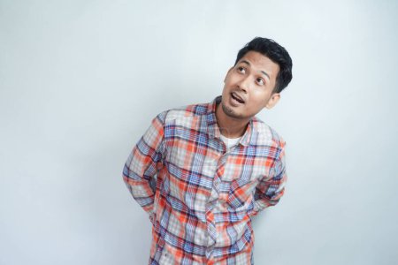 Photo for Adult Asian man wearing flannel shirt looking above him with surprised expression - Royalty Free Image