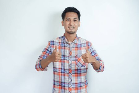 Erwachsener asiatischer Mann zeigt fröhlichen Ausdruck und gibt zwei Daumen nach oben