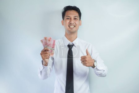 Photo for Asian businessman smiling and give thumb up while holding money - Royalty Free Image