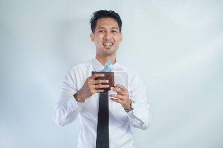 Foto de Adulto asiático hombre sonriendo feliz mientras muestra su cartera llena de papel moneda - Imagen libre de derechos