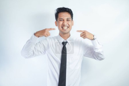 Atractivo asiático hombre grande sonriendo mientras señala el dedo a sus dientes