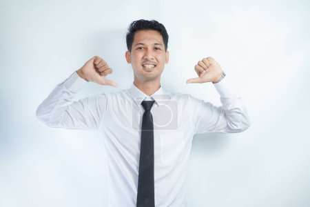 Adult Asian man pointing to plain white shirt with tie that he wearing with happy expression