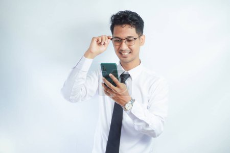 Adult Asian man laughing out loud when looking to his mobile phone
