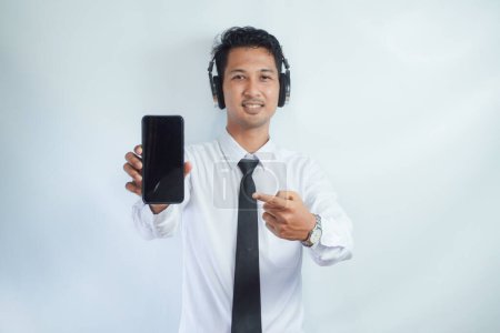 Photo for Adult Asian man smiling confident while pointing finger to blank handphone screen - Royalty Free Image