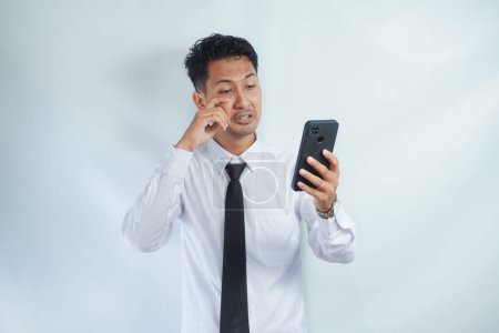 Photo for Adult Asian man showing stress expression when answering a phone call - Royalty Free Image